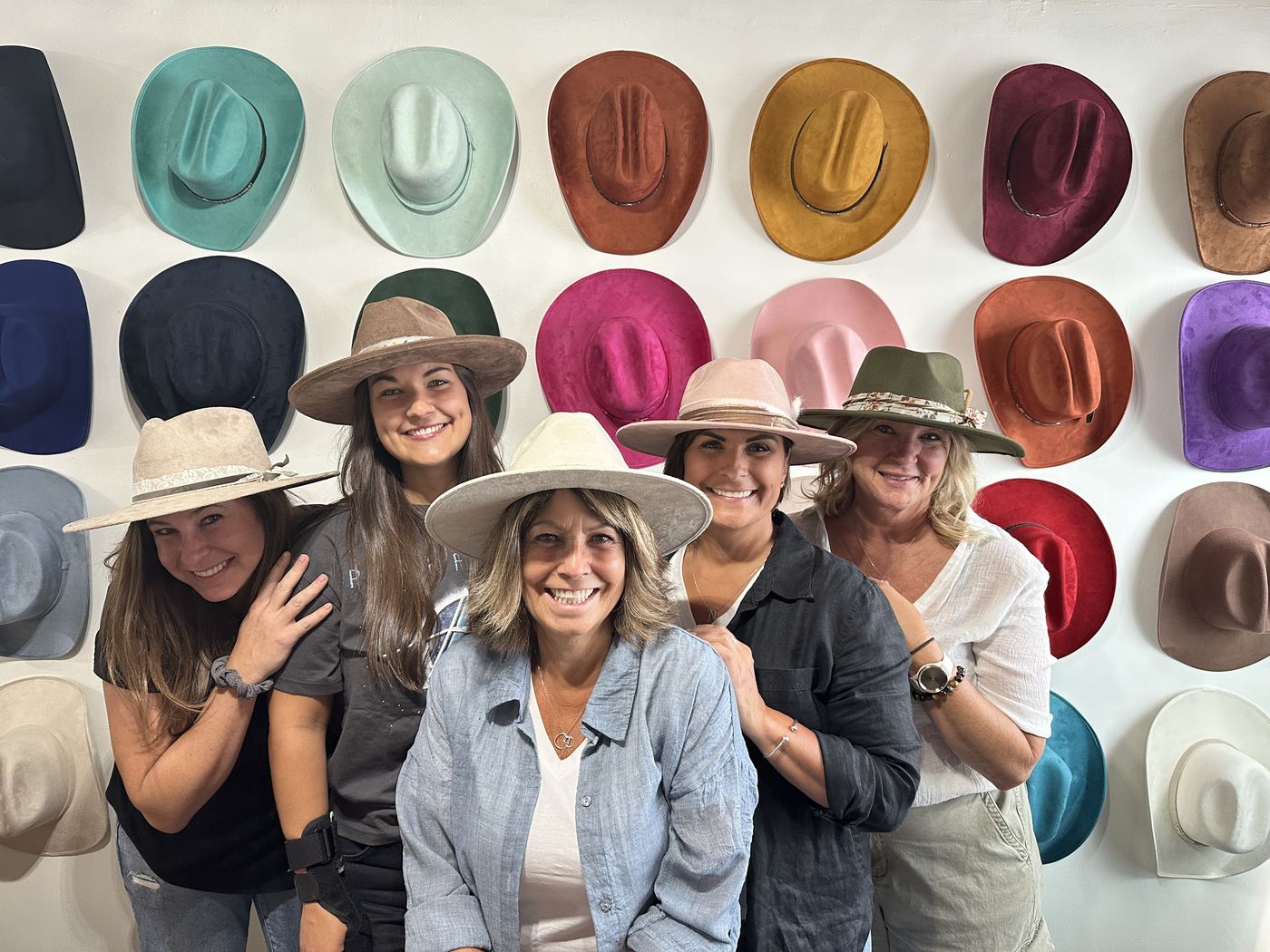 Guests posing in front of a colourful hat wall at a birthday party
