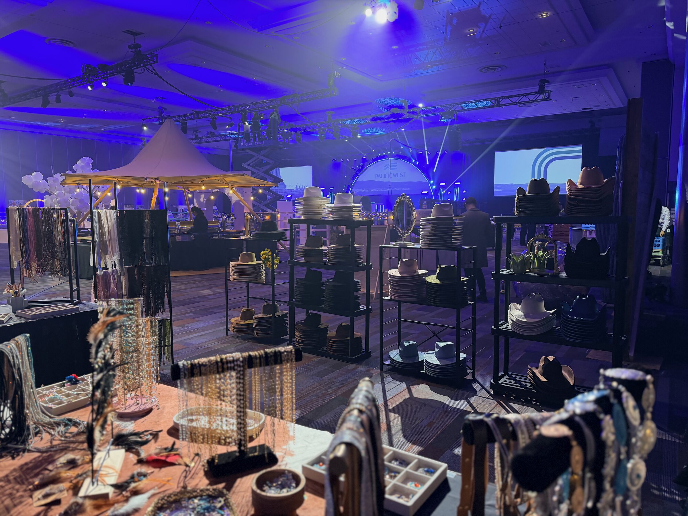 Saddle N Spurs hat bar display shelves and accessory tables lit in blue at a Vancouver corporate convention