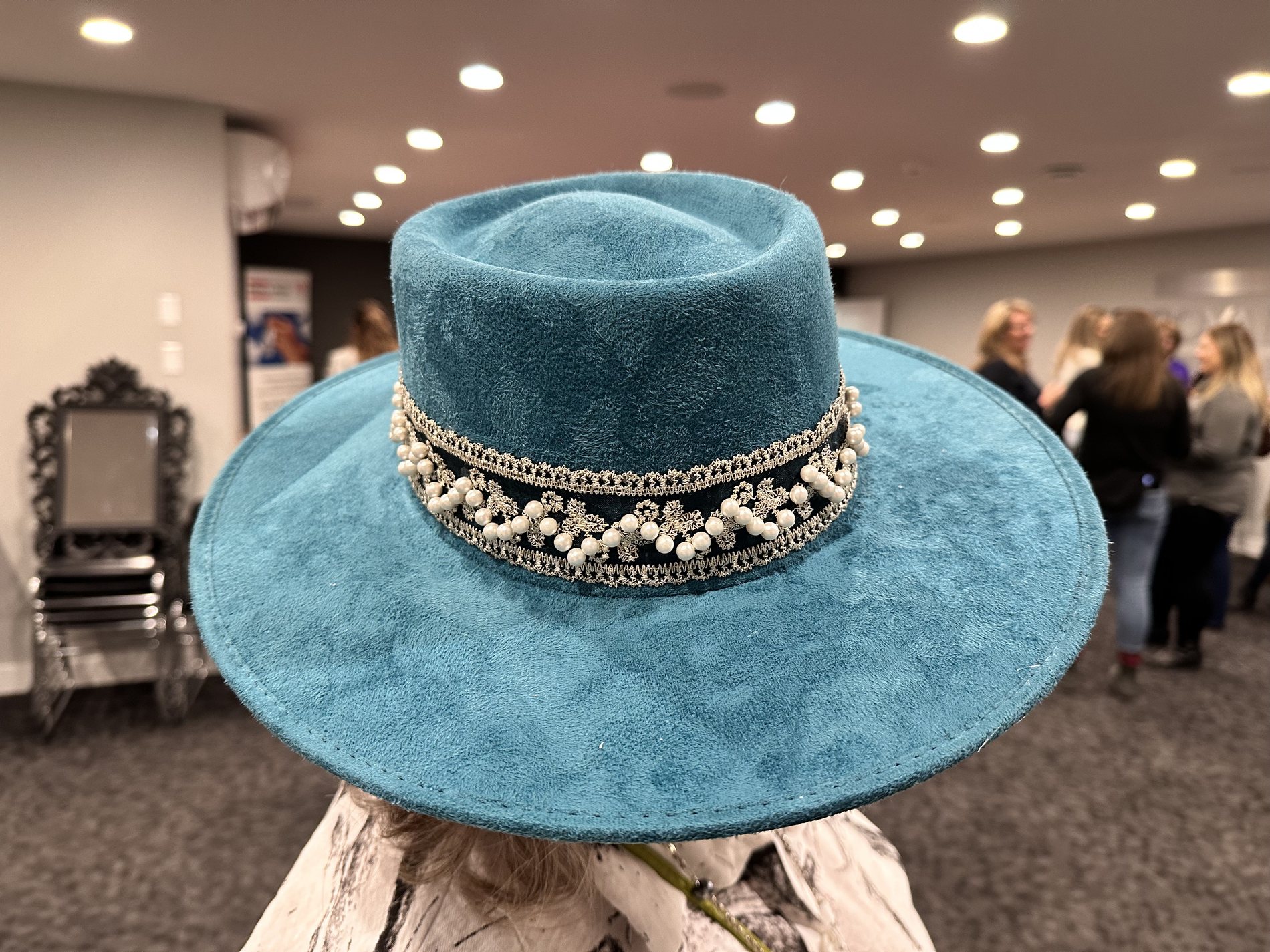 Custom teal hat styled with a pearl and silver trim band at a Royal LePage event