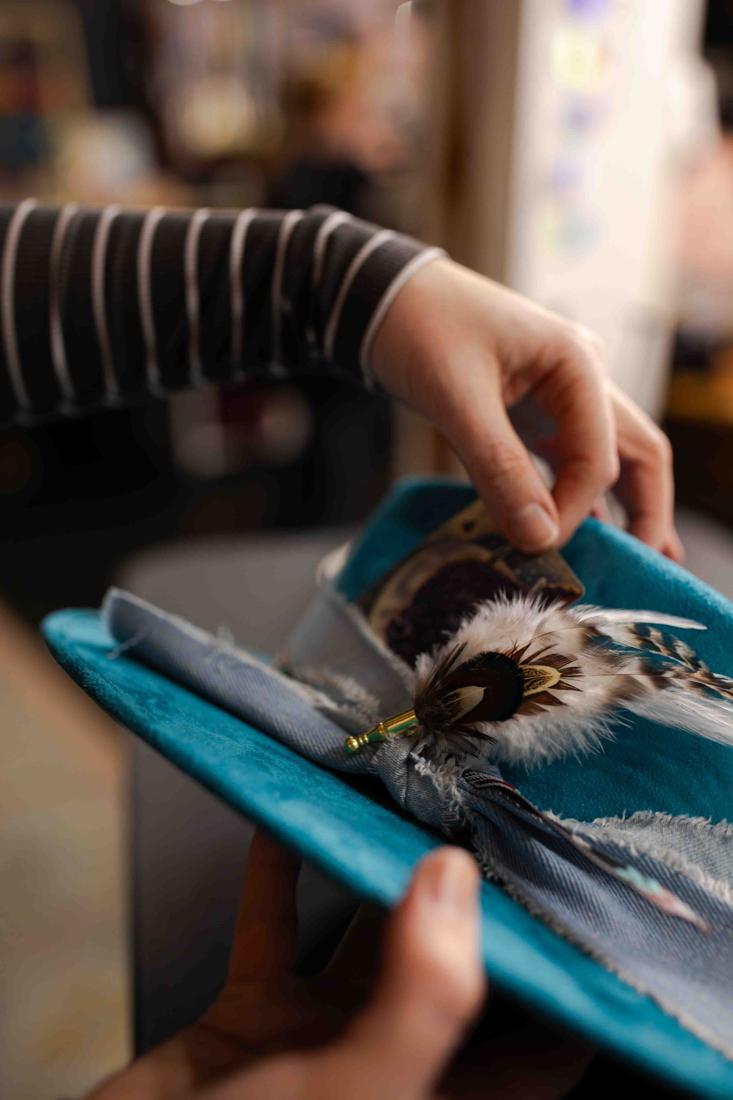 Close-up of feathers and accessories being added to a custom hat band