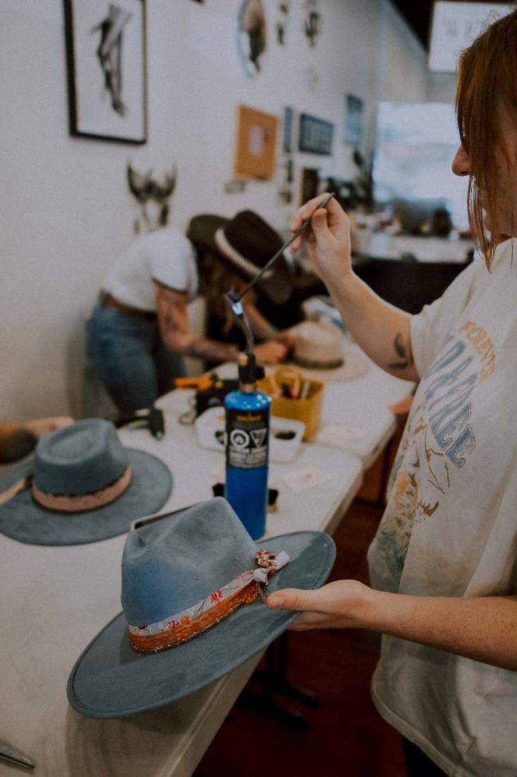 Live hand-branding a custom cowboy hat with a torch at the Saddle N Spurs hat bar