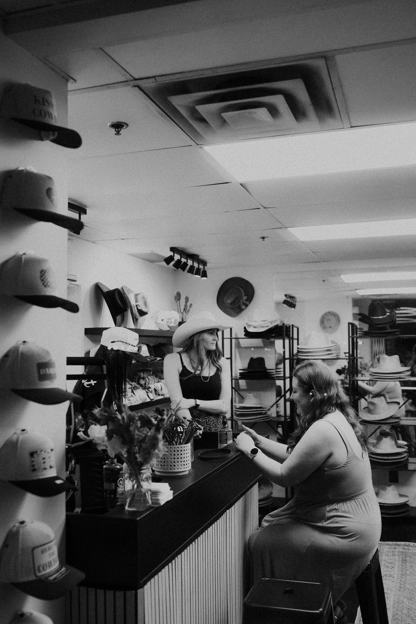 Black and white photo of a customer chatting with staff at the Saddle N Spurs Kelowna counter
