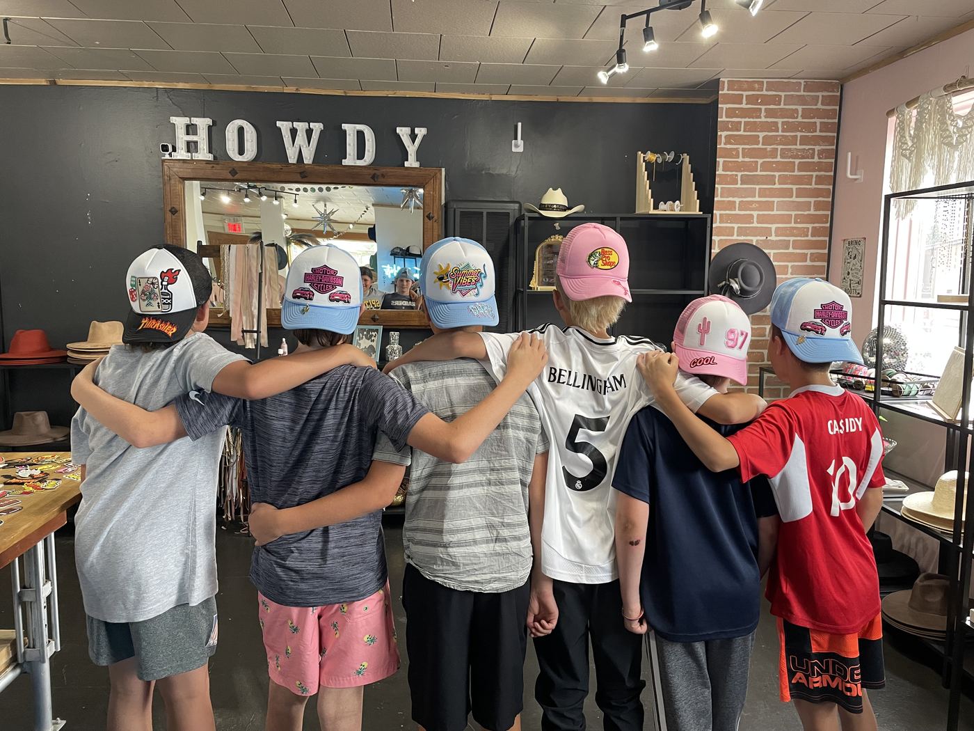 Kids showing off their custom trucker hats from behind at a Saddle N Spurs birthday party