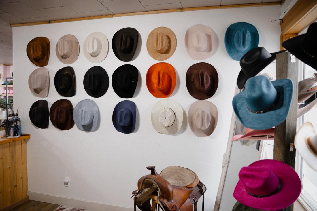 Rainbow wall of hats inside the Saddle N Spurs shop, saddle in foreground