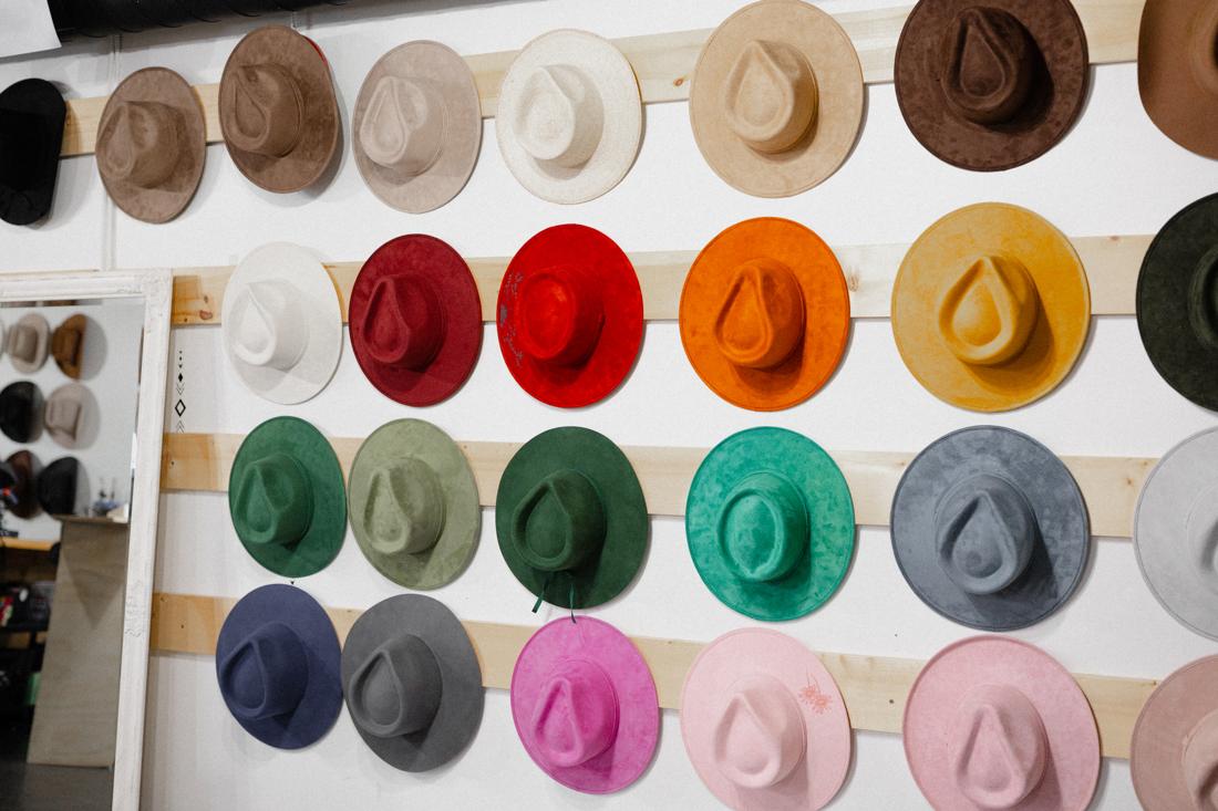 A rainbow wall of custom felt cowboy hats inside the Saddle N Spurs shop