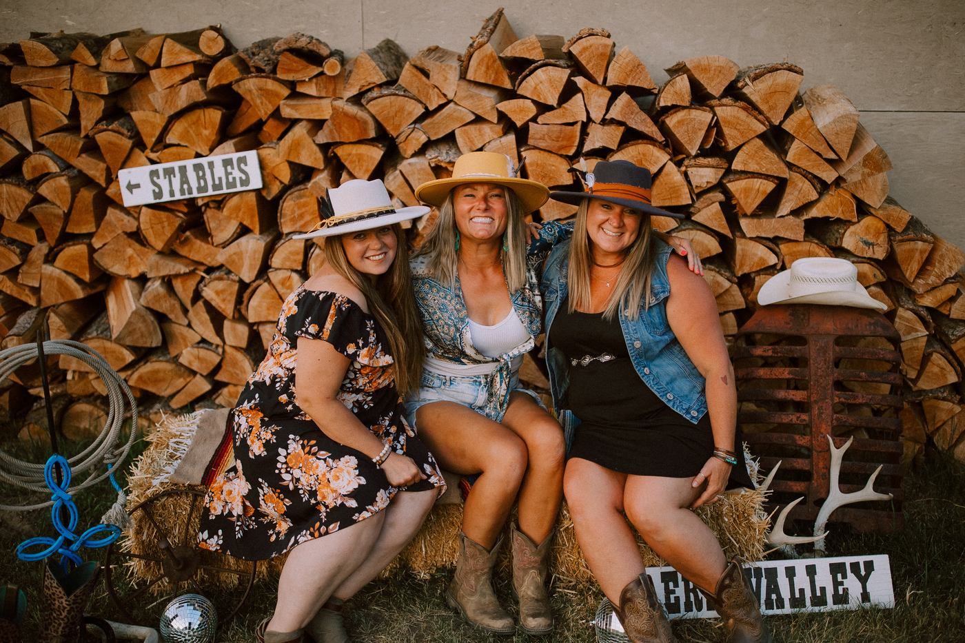 Three guests posing by the Erin Valley stables sign at sunset