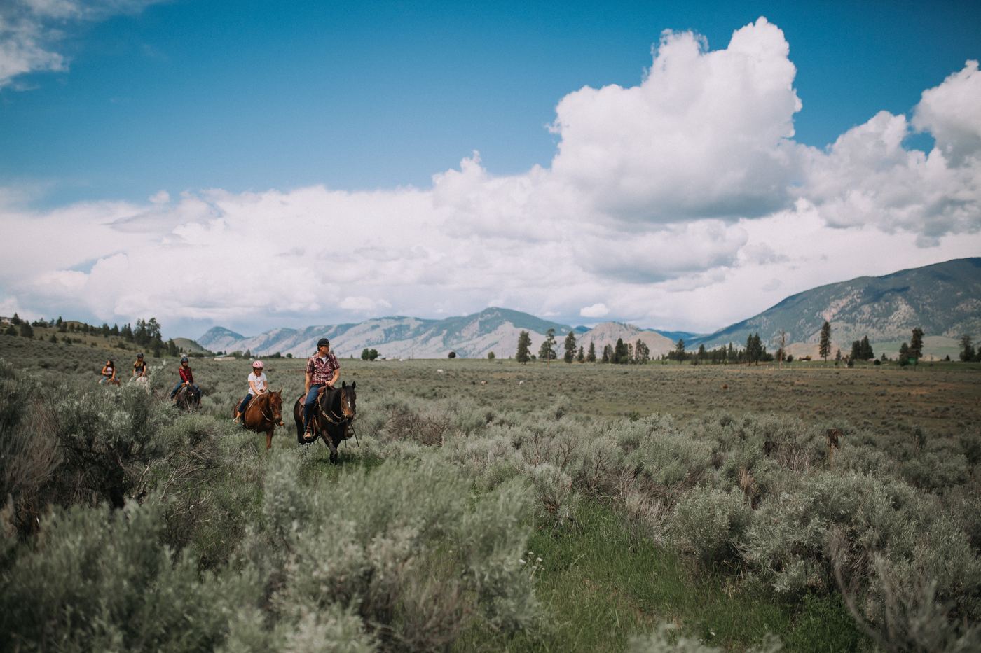 Family riding horses together through the sagebrush at Erin Valley