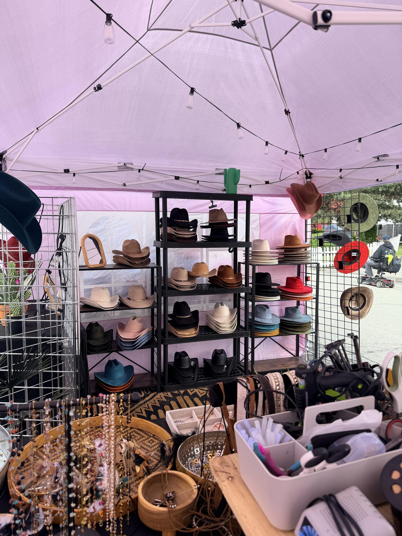 Close-up of hat accessories and charms styled in a wood crate at the Cloverdale Rodeo booth