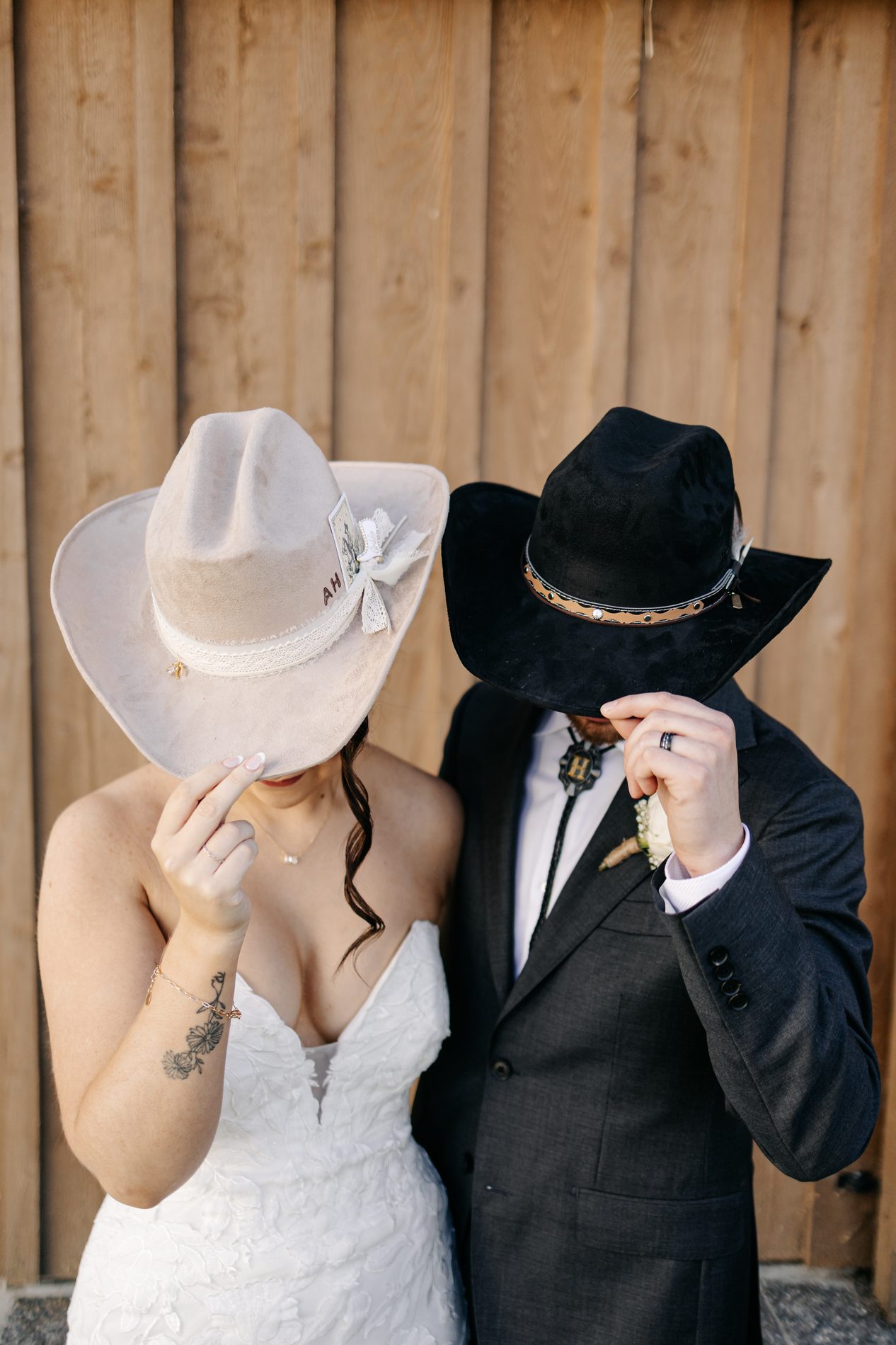 Bride and groom peeking out from under their custom cream and black wedding hats