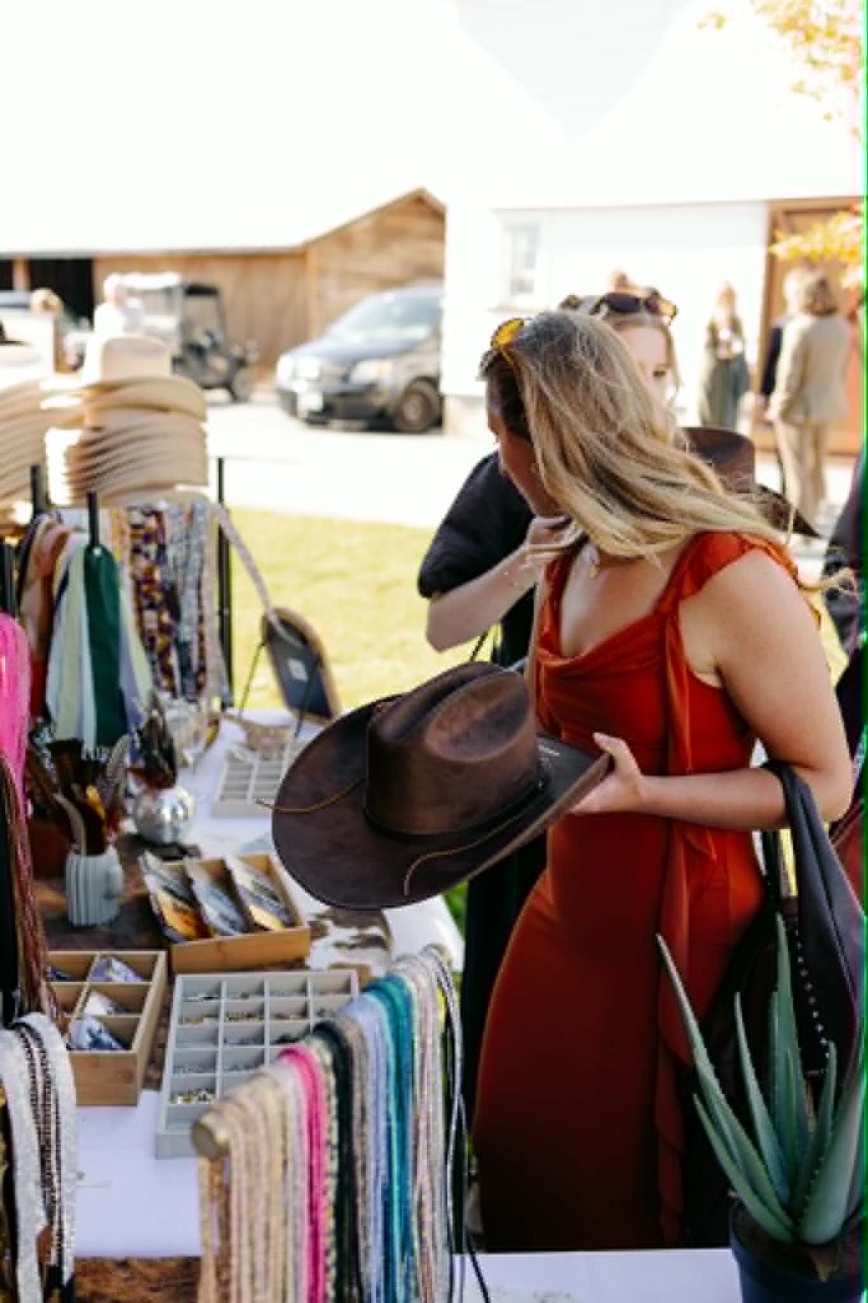 Wedding guest browsing the ribbon and accessory station, holding a brown hat