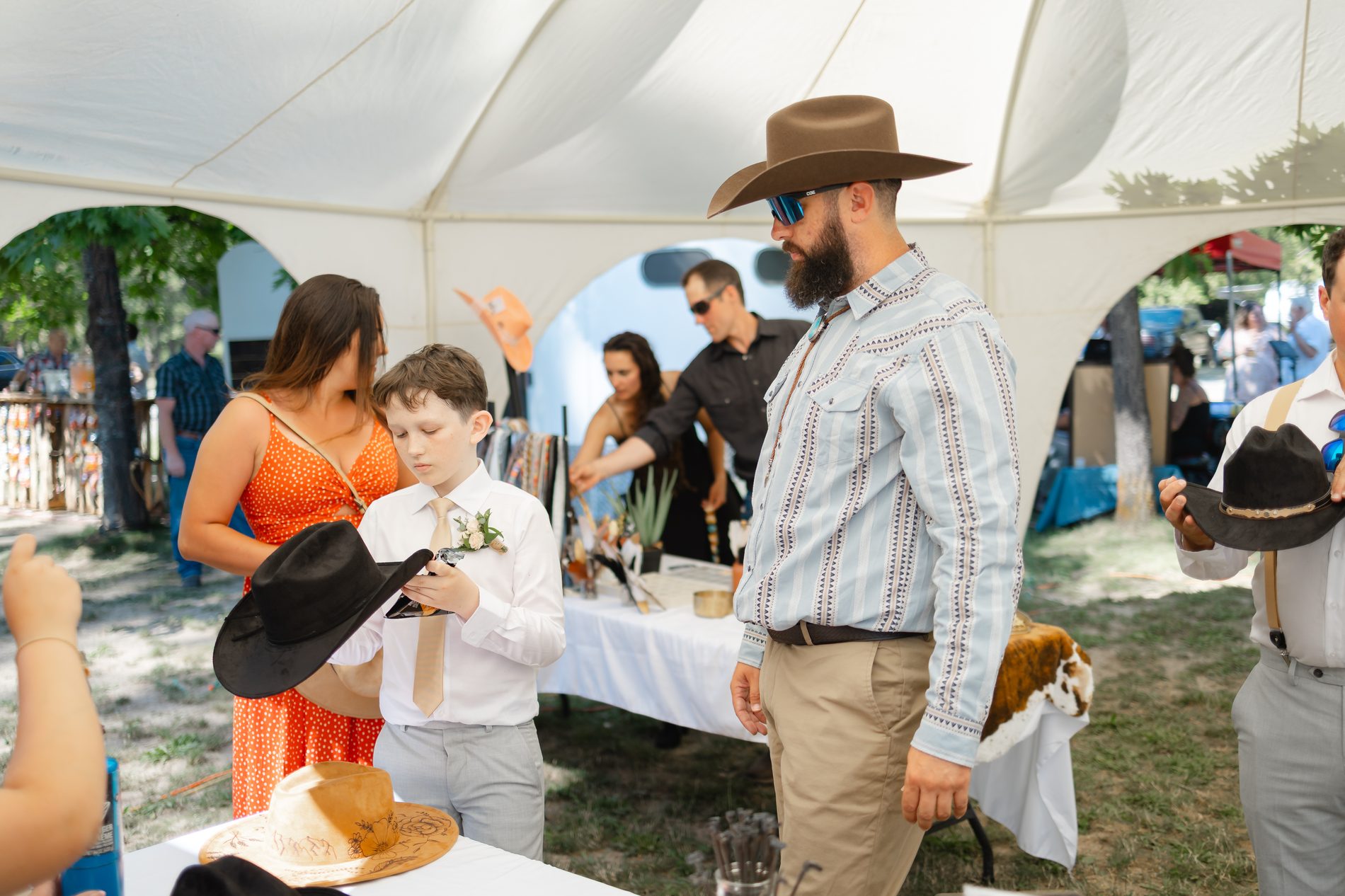 A young wedding guest trying on a black cowboy hat at the styling table